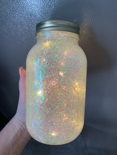 a hand holding a mason jar with holographics on it