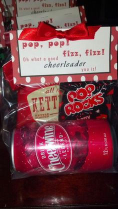 some candy and soda wrapped in plastic on a table with a sign that says pop pop fizz, cheerleader