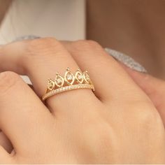 a woman's hand wearing a gold ring with three small diamonds on the band