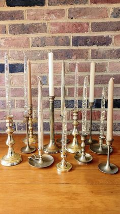 a group of candles sitting on top of a wooden table next to a brick wall