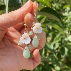 Elevate your style with our cute and delicate Spring Green Dangle Earrings. Adorned with white shell flowers, these lightweight and versatile dangles add a touch of nature-inspired elegance. Perfect for both casual and special occasions, they complement any outfit effortlessly. Whether it's a springtime brunch, garden party, or even a beach wedding, these earrings are a must-have. They also make a wonderful gift for holidays like Mother's Day, birthdays, or anniversaries. Surprise your loved ones, friends, or even treat yourself to these charming earrings that capture the essence of beauty and grace. Elegant Handmade Summer Flower Earrings, Summer Flower Charm Jewelry, Elegant Flower Charm Earrings For Summer, Elegant Flower Jewelry For Summer, Elegant Summer Flower Pendant Jewelry, Elegant Summer Flower Jewelry, Dangle Flower Earrings As Gift For Her, Feminine Spring Dangle Earrings, Spring Feminine Dangle Jewelry