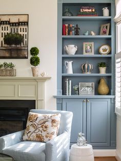 a living room with blue bookcases and a white chair in front of a fireplace