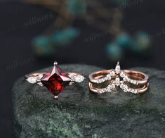 two different types of engagement rings on top of a rock, one with a red diamond and the other with white diamonds