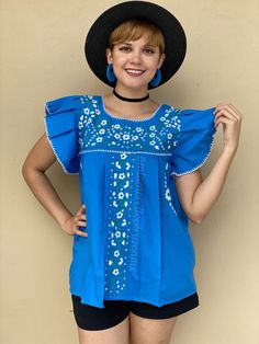 "Blue ruffled sleeve floral embroidered mexican blouse women, boho hippie modern top, mexico beach vacation, hand embroidered flowers Look unique and be the center of the party with this hand-embroidered Mexican blouse, this top will definitely eye catching. This is a traditional Mexican top with a twist; ruffled sleeve, one of Mi Amorcito Corazon exclusive designs. Blue top with gorgeous details of white and teal embroidered flowers. Top is loose fit and flowy. Fits size SMALL (Tag reads M, but Flowy Cotton Blouse With Floral Embroidery, Bohemian Flutter Sleeve Tops For Spring, Flowy Floral Embroidery Blouse For Vacation, Bohemian Flowy Embroidered Top, Summer Bohemian Blouse With Ruffles, Summer Embroidered Top With Flutter Sleeves, Summer Embroidered Blouse With Flutter Sleeves, Summer Flutter Sleeve Embroidered Top, Bohemian Ruffled Summer Blouse