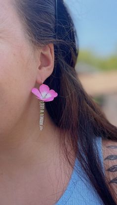 a close up of a person wearing earrings with a flower on the side of their ear