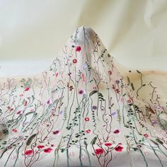 a white cloth with red and green flowers on it, sitting on top of a table