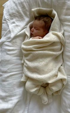 a baby wrapped in a blanket on top of a bed