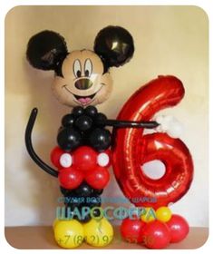 a mickey mouse balloon with the number six on it's side and balloons in the shape of numbers