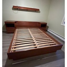 a bed with wooden slats and drawers in a room that has no carpet on the floor