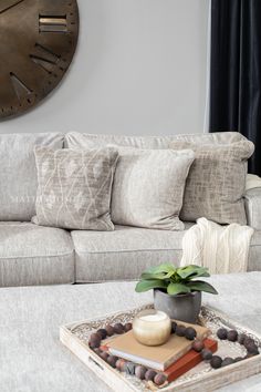 a living room with a couch, coffee table and clock on the wall above it