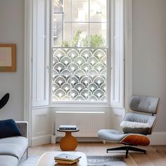 a living room with a chair, ottoman and window