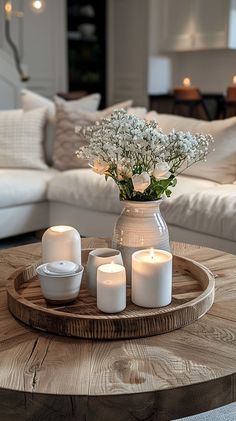 a table with candles and flowers in a vase on top of it next to a couch