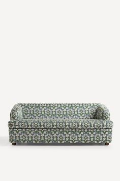 a green and white patterned couch sitting on top of a wooden floor