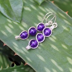 "Three juicy purple 6mm amethyst beads, stacked and outlined with sterling silver wire. This glowing purple shade is one of the hottest colors for the season, and these elegant dangles are sure to get noticed! They measure 1-5/8\" long including the sterling silver kidney earwires. Amethyst is the birthstone for February. Can also be made with 14kt gold filled wire." Purple Round Spiritual Earrings, Spiritual Round Purple Earrings, Spiritual Purple Round Earrings, Nickel-free Beaded Earrings As Gift, Nickel-free Beaded Earrings For Gifts, Nickel-free Round Bead Earrings As Gift, Nickel-free Purple Beaded Round Earrings, Wire Wrapped Amethyst Drop Earrings, Purple Spiritual Drop Earrings