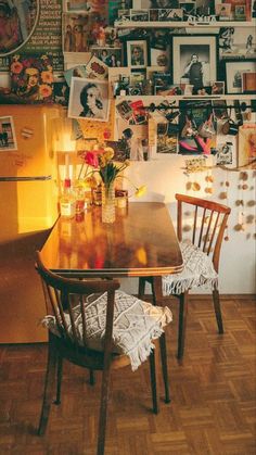 a dining room table and chairs in front of a refrigerator with pictures on the wall