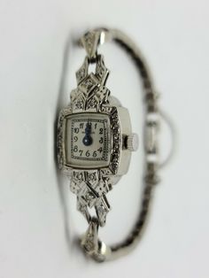 14K White Gold Vintage MAYFAIR Diamond Wrist Watch 6.5" inches with a 3" Safety Chain Beautiful Vintage Look with White Dial and Black Arabic Numbers and Blue Steel Hands. 65 Round diamonds for a total of 0.30 carats and a total weight of 12.84 Grams Includes GAL Appraisal MSRP $3,200 Condition is "Pre-owned" and in working condition with some signs of wear and stretch Shipped Free with USPS Priority Mail Art Deco Evening Watch With Diamond Hour Markers, Art Deco Platinum Evening Watches, Platinum Art Deco Evening Watches, Vintage Diamond Watch With Rectangular Dial For Formal Occasions, Vintage Diamond Watch With Rectangular Dial For Formal Events, Art Deco Platinum Diamond-studded Jewelry, Art Deco Platinum Jewelry With Diamond Hour Markers, Classic Formal Jewelry And Watches With 17 Jewels, Timeless Engraved Watches For Anniversary