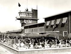 an old black and white photo of people sitting at tables in front of a building