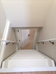 there is a staircase leading up to the door in this house with white walls and wood flooring