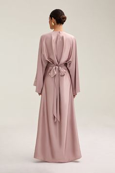 Indulge in luxury with the Batool Satin Maxi Dress. Its loose wide sleeves and lustrous satin fabric exude elegance, while the adjustable tie waist flatters your figure. Versatile design makes it perfect for Eid and beyond. Elevate your style with this exclusive piece. Model is 5'7 wearing size XS/58" Elegant Long Sleeve Dress With Tie Fastening, Tie Back Wrap Dress For Party, Elegant Flowy Dress With Kimono Sleeves, Flowy Tie Waist Dress For Formal Occasions, Elegant Tie Back Wrap Dress, Formal Flowy Dress With Tie Waist, Formal Belted Flowy Dress, Elegant Maxi Dress With Tie Waist And Kimono Sleeves, Elegant Wrap Maxi Dress With Draped Sleeves