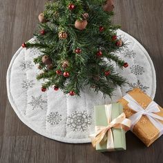 a small christmas tree with presents on the floor next to it and a white towel