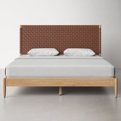 a bed with two pillows on top of it and a headboard made out of wood