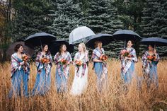 a group of women holding umbrellas standing next to each other in tall grass with trees behind them