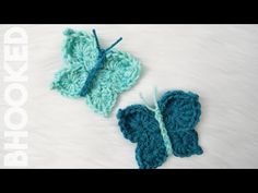 two crocheted butterflies sitting next to each other on a white furnishing