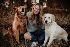 a woman is sitting with two dogs in the woods