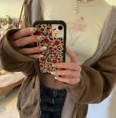 a woman holding up her phone case with flowers on it