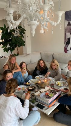 a group of women sitting around a table with food and drinks in front of them