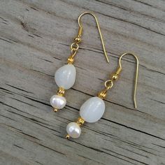 "Two classic jewels in brilliant white: milky white Peruvian opals are paired with white freshwater pearls in a stunningly classic look 💕  These are the perfect jewelry gift for someone with a birthday in June (birthstone= pearl!) or October (birthstone= opal!). 💕 Peruvian opals 💕 Freshwater pearls 💕 22K gold-plated wires & accents This pair of opals are milky white and faintly translucent.  Their faint bluish-white shade is more noticable against the creamy white of the pearls. Did you know Dainty White Opal Jewelry, White Opal Birthstone Jewelry, White Teardrop Mother Of Pearl Jewelry, Delicate White Opal Jewelry, Delicate White Mother Of Pearl Jewelry, Classic White Mother Of Pearl Earrings, Dainty White Pearl Earrings, White Pearl Charm Earrings, Delicate White Jewelry With Matching Earrings