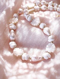 Flanked with luminescent natural white baroque pearls, puka shells, and carved mother of pearl, this unique luxurious pearl choker necklace evokes visions of Hawaii's white sands and soothing shores. Layer this with other shimmering beauties and you'll be ready for your tropical escape. ✦ DETAILS ✦✧ Name: Keao (keh-AH-oh) - The light of the day.✧ Adjustable Necklace.✧ White Puka Shells.✧ Genuine Baroque Freshwater Pearls.✧ Carved Mother of Pearl Seashells.✧ 14kt Gold Filled with lobster clasp.✧ Handmade White Pearl Shell Necklace, White Shell-shaped Jewelry With Pearl Pendant, Handmade White Shell-shaped Pearl Necklace, White Shell With Pearl Pendant, White Shell-shaped Pearl Drop Necklace, Adjustable Shell-shaped Pearl White Jewelry, White Shell-shaped Pearl Pendant Jewelry, Pearl White Shell-shaped Pearl Chain Jewelry, White Shell Necklace With Pearl Charm