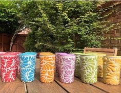 several colorful cups sitting on top of a wooden table