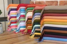 a pile of different colored blankets sitting on top of a wooden floor next to a brick wall