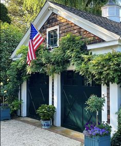 an american flag is hanging on the side of a house with green doors and windows