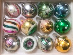 a box filled with different colored christmas ornaments