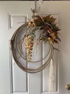 a wreath hanging on the front door with dried flowers and foliages attached to it