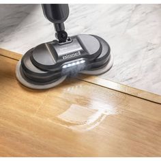 a person using a vacuum to clean a wooden floor