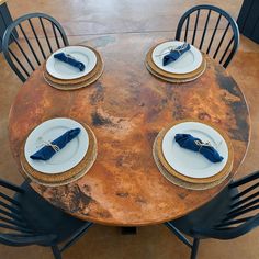 the table is set with plates and napkins on it, along with black chairs