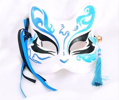 a white mask with blue designs and a tassel on the side that says jester