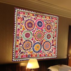 a bed room with a neatly made bed and a large tapestry hanging on the wall