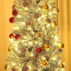 a white christmas tree with gold and red ornaments