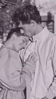 an old black and white photo of two people embracing each other in front of a building