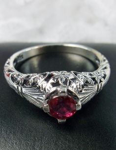 <> Made To Order This is a Victorian/Edwardian reproduction ring in sterling silver filigree with a natural red ruby gemstone solitaire. This full cut round cut red ruby gemstone is 4mm in diameter. The inside of the band is marked 925 for sterling. Notice the beautiful floral design of the silver filigree setting and band. This is a lovely rendition of an Antique filigree ring, and it is ready to wear. A gift ring box is included and all rings are shipped in the ring box for safekeeping. Traditional Oval Filigree Wedding Ring, Traditional Hallmarked Filigree Ring For Wedding, Traditional Oval Ruby Ring For Anniversary, Traditional Oval Engraved Ring With Intricate Design, Traditional Oval Engraved Anniversary Ring, Traditional Ruby Ring With Intricate Design As Gift, Traditional Oval Filigree Ring With Intricate Design, Traditional Hallmarked Filigree Ring For Formal Occasions, Red Victorian Engraved Jewelry