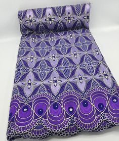 a purple and blue patterned bed spread with matching pillow cases on it's sides