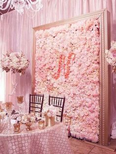 a large floral wall with chairs and tables set up for a wedding reception in front of a chandelier