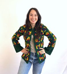 a woman standing with her hands on her hips and wearing a colorful knitted jacket