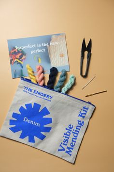 a bag with yarn, scissors and knitting needles on it next to an advertiser's book