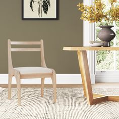 a chair sitting next to a table with a vase on it and flowers in the background