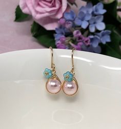 These one of a kind flowering beauties feature soft, blush pink Swarovski Crystal pearls that are meticulously wrapped in 14kt yellow gold filled wire. The braided detailing looks amazing with these pearls. Accented with gold-dusted, aqua Czech glass flowers and gracefully suspended from handcrafted French ear wires. These are perfect for Spring, Summer and for bridesmaids gifts! - All components are 14kt yellow gold filled. - Swarovski Crystal pearls, Czech Glass flower beads. - Pearl dangles a Whimsical Pink Dangle Flower Earrings, Delicate Drop Earrings For Spring, Handmade Floral Drop Earrings For Spring, Elegant Teardrop Earrings For Spring, Feminine Jewelry With Matching Earrings For Spring, Delicate Dangle Earrings For Spring, Whimsical Pink Earrings With Flower Charm, Handmade Flower Earrings As Feminine Gift, Handmade Feminine Flower Earrings For Gifts